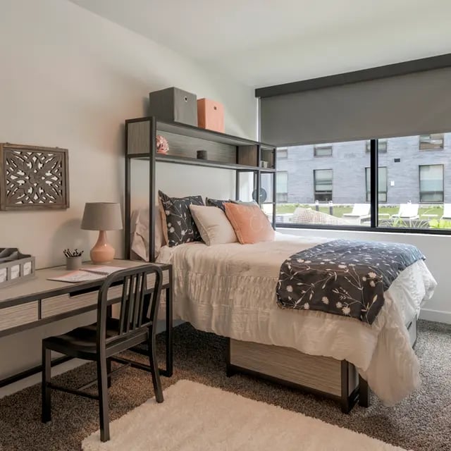 Bed desk lamp chair storage wall art bedroom at 505 on Walnut Apartments in Syracuse Student Accommodation