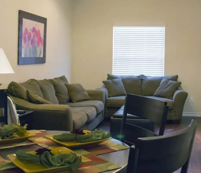 Two couches framed art and dining table living room at The Estate on Third in Waco Student Accommodation