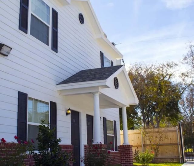 White building with dark shutters and entrance exterior at The Estate on Third in Waco Student Accommodation