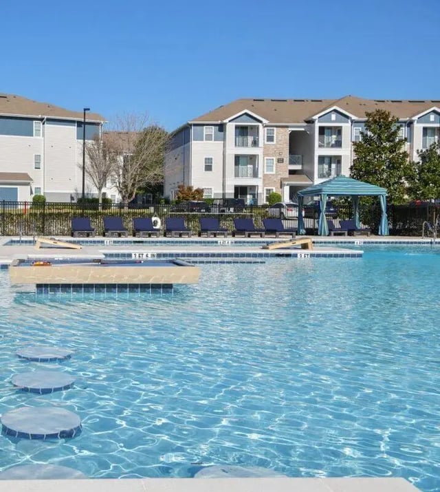 Pool lounge chairs pool and apartment buildings exterior at The Hudson in Statesboro Student Accommodation