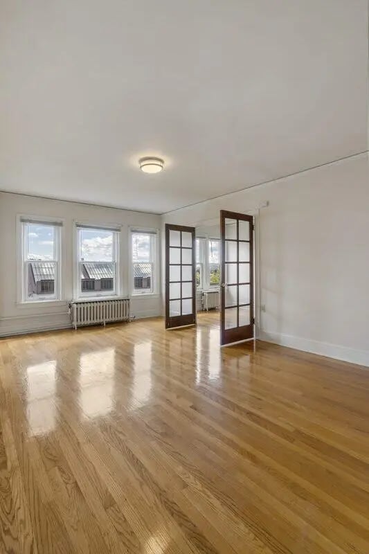 Empty room with polished hardwood floor and doors living room at Commodore Duchess Apartments in Seattle Student Accommodation