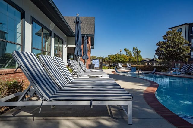 Striped lounge chairs beside a swimming pool exterior at Midtown 905 in Denton Student Accommodation