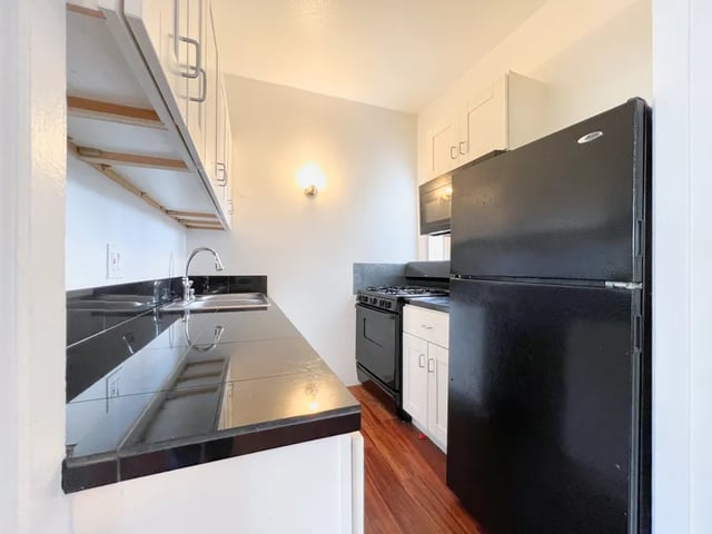 Black refrigerator stove sink cabinets kitchen at 1329 W 36th St in Los Angeles Student Accommodation