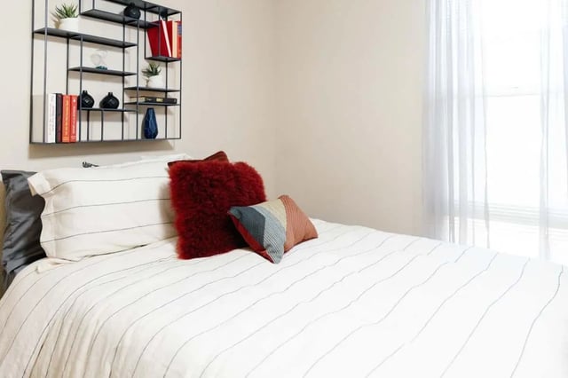 Bed with striped bedding and decorative pillows bedroom at The Scarlet in Lubbock Student Accommodation