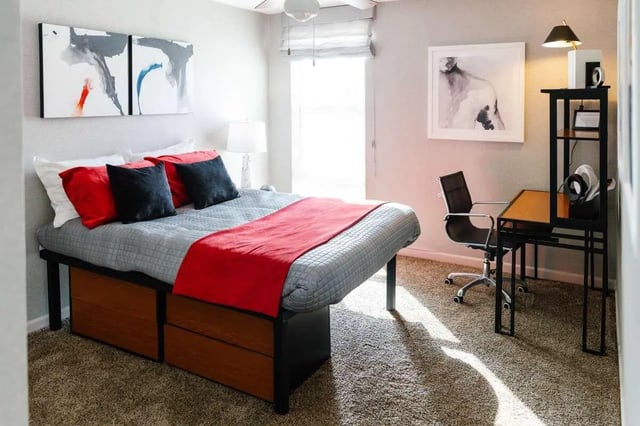 Bed with red and black pillows desk and chair bedroom at The Scarlet in Lubbock Student Accommodation