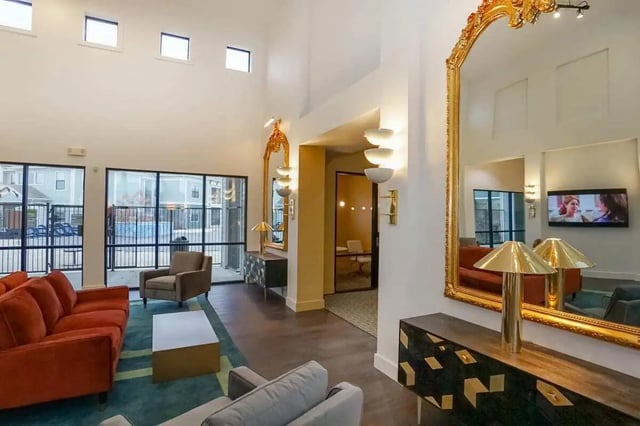Orange sofas white table large gold mirror living room at The Domain at Columbia in Columbia Student Accommodation