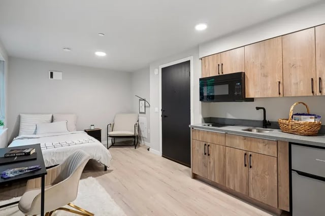 Bed armchair desk kitchen studio apartment at Clara Apartments in Seattle Student Accommodation