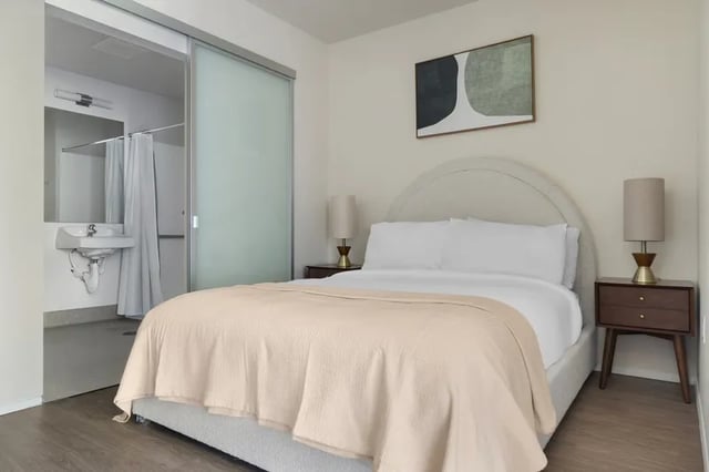 Bed nightstand lamp and bathroom sink bedroom at Clara Apartments in Seattle Student Accommodation