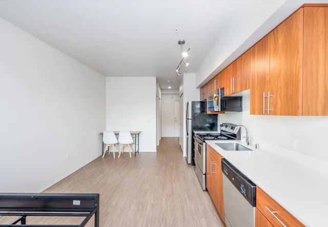 Bed frame chairs table and kitchen area living room at Clara Apartments in Seattle Student Accommodation