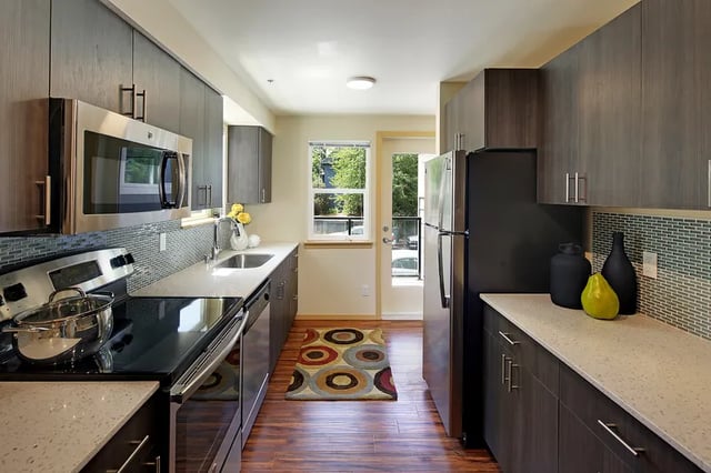 Stainless steel appliances dark cabinets and countertops kitchen at Clara Apartments in Seattle Student Accommodation