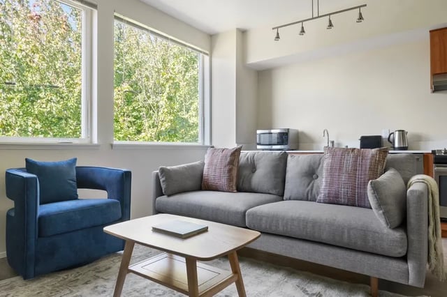 Blue armchair grey couch coffee table living room at Clara Apartments in Seattle Student Accommodation