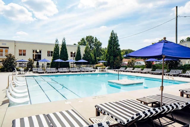Swimming pool with lounge chairs and umbrellas outdoor area at The Vic in Greensboro Student Accommodation