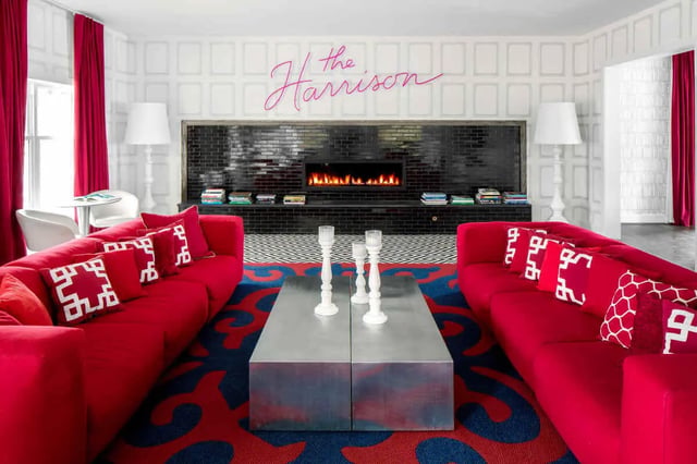 Red sofas modern fireplace patterned rug living room at The Harrison in Harrisonburg Student Accommodation