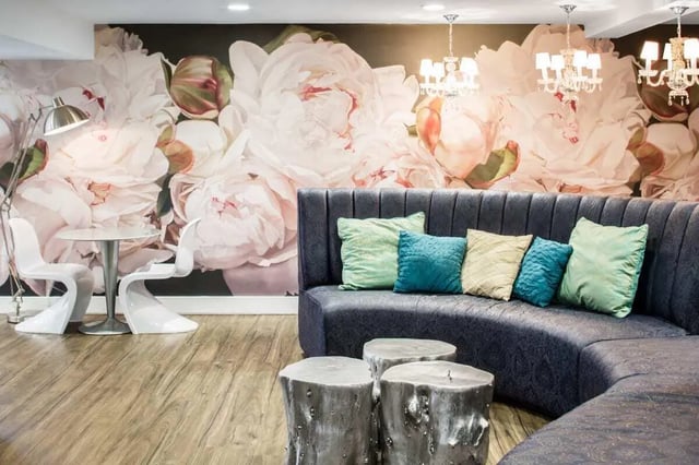 Curved sofa with pillows flower mural two chairs living room at The Harrison in Harrisonburg Student Accommodation
