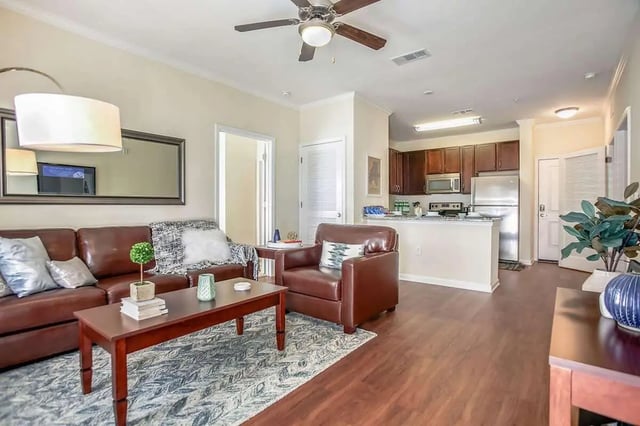 Brown leather sofa armchair coffee table kitchen living room at West 22 in Kennesaw Student Accommodation