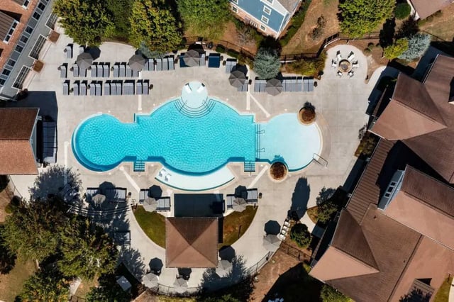Swimming pool with lounge chairs and umbrellas exterior at West 22 in Kennesaw Student Accommodation