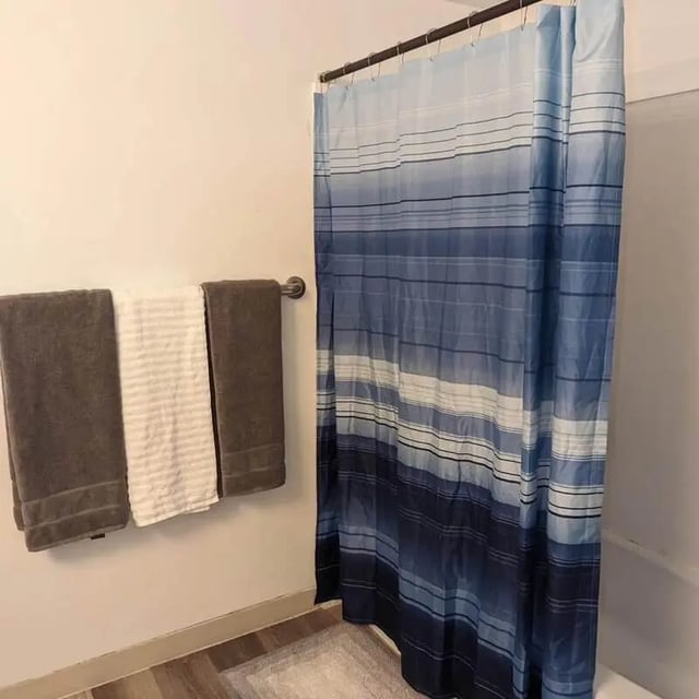 Towels and blue striped shower curtain bathroom at Crestwood Rexburg Apartments in Rexburg Student Accommodation
