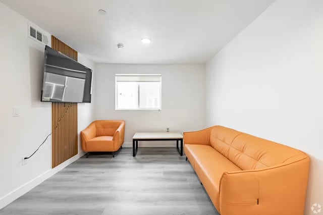Orange sofa armchair coffee table TV living room at 1476 W 35th St in Los Angeles Student Accommodation