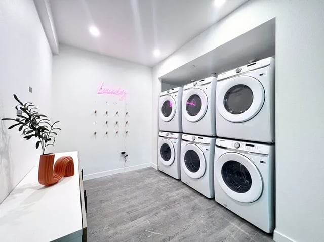 Stacked washers and dryers with neon sign laundry sign laundry area at 1587 W 35th St in Los Angeles Student Accommodation