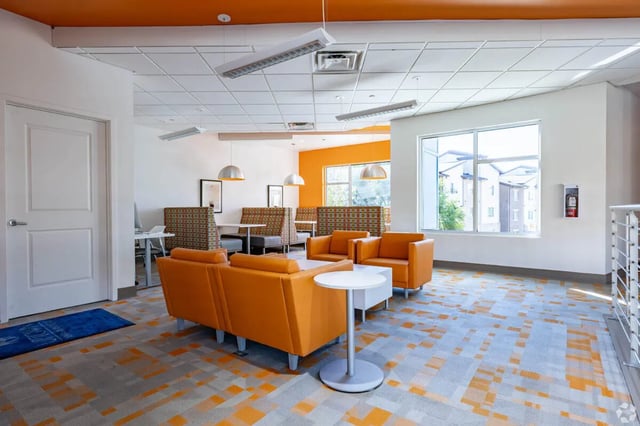 Orange couches booth seating white tables common area at 65 West in Cincinnati Student Accommodation