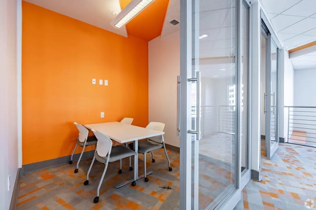 Table with chairs next to orange wall study area at 65 West in Cincinnati Student Accommodation