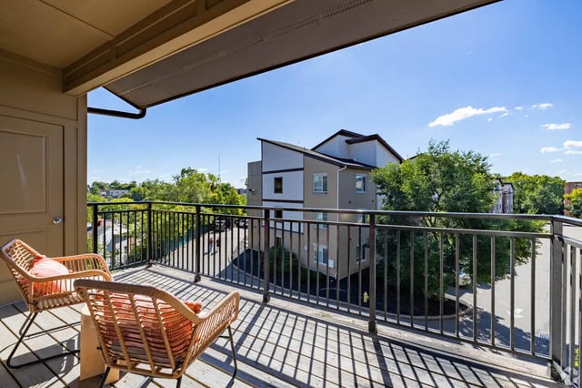 Two wicker chairs on sunny balcony exterior at 65 West in Cincinnati Student Accommodation