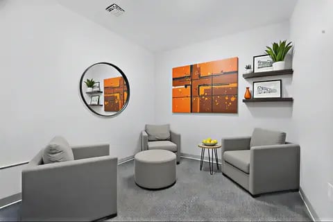 Gray armchairs round ottoman art abstract painting living room at Polk On Third - Off Campus Student Housing in Bethlehem Student Accommodation