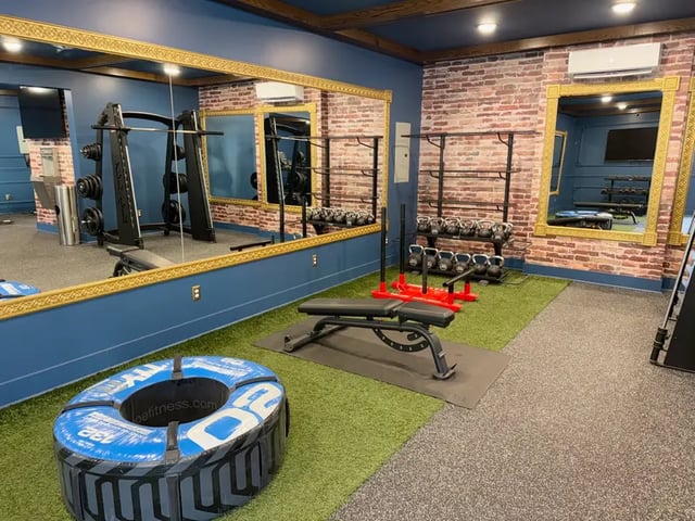 Weights bench tire sleds racks gym area at The French Quarter Apartments in Auburn Student Accommodation