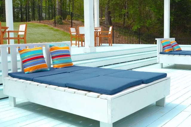White deck lounge with blue cushions and pillows outdoor seating area at The French Quarter Apartments in Auburn Student Accommodation