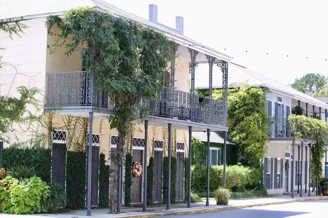 Two-story building with balconies and greenery exterior at The French Quarter Apartments in Auburn Student Accommodation