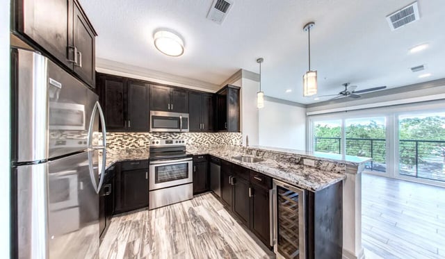 Stainless steel appliances dark cabinets granite counters kitchen at Cascades Luxury Apartments in Gainesville Student Accommodation