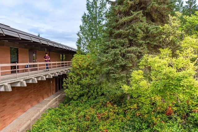Student on walkway by brick building and trees exterior at 7000 Campus Living Apartments in Shoreline Student Accommodation