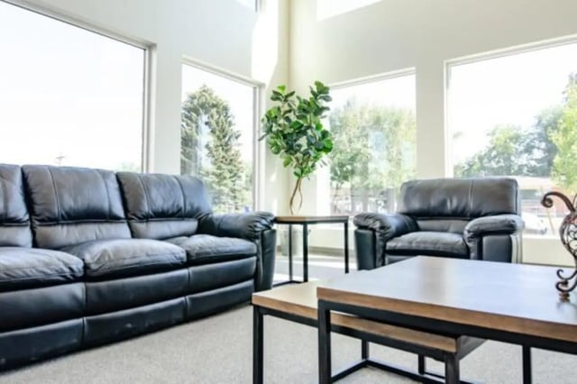 Black leather sofas tables large windows living room at Sundance Apartments - BYU-Idaho Approved Housing in Rexburg Student Accommodation