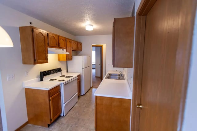 Cabinets stove refrigerator sink kitchen at Copperfield Court in Morgantown Student Accommodation