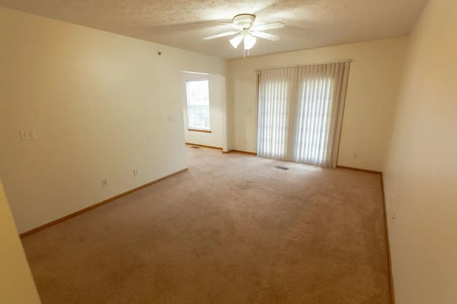 Carpeted living room with ceiling fan and sliding glass doors living room at Copperfield Court in Morgantown Student Accommodation