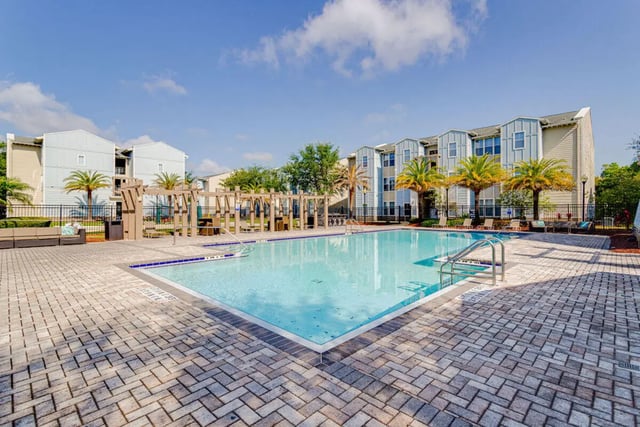 Apartment buildings with a pool and palm trees Exterior at Hawks Landing in Oxford Student Accommodation