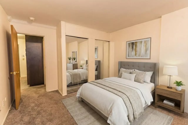Bed with grey headboard mirror closet lamp bedroom at Waters Edge Apartments in East Lansing Student Accommodation