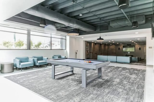Pool table blue chairs large windows common area at Current Midtown Apartments in Williamsburg Student Accommodation
