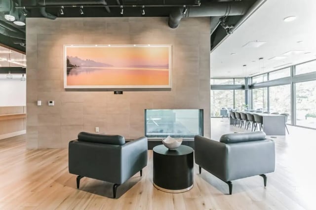 Two armchairs, round table, fireplace, artwork communal lounge at Current Midtown Apartments in Williamsburg Student Accommodation