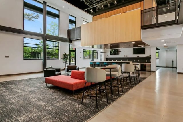 Modern lounge area with red sofa and bar seating lounge at Current Midtown Apartments in Williamsburg Student Accommodation