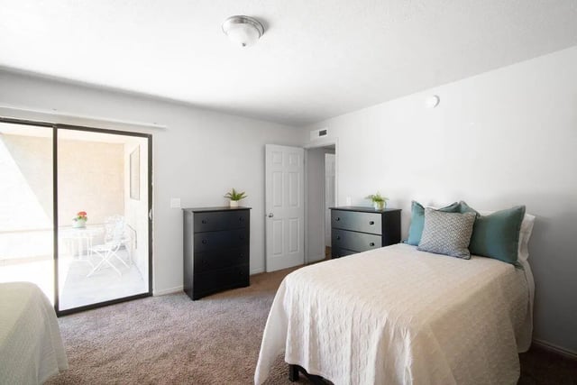 Two beds dressers patio door bedroom at 7th & University Apartments in St. George Student Accommodation