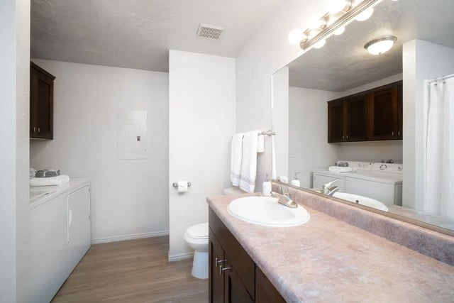 Sink toilet washer and cabinets bathroom at 7th & University Apartments in St. George Student Accommodation