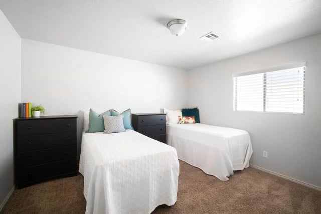 Two beds black dressers and pillows bedroom at 7th & University Apartments in St. George Student Accommodation