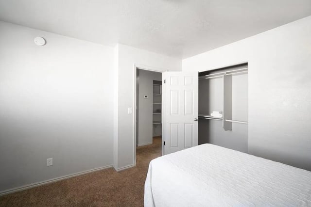 White bed open closet shelves bedroom at 7th & University Apartments in St. George Student Accommodation
