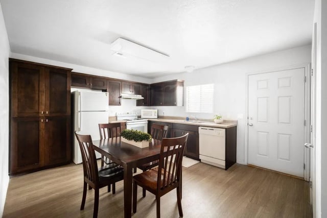 Dark wood cabinets white fridge dining table kitchen at 7th & University Apartments in St. George Student Accommodation