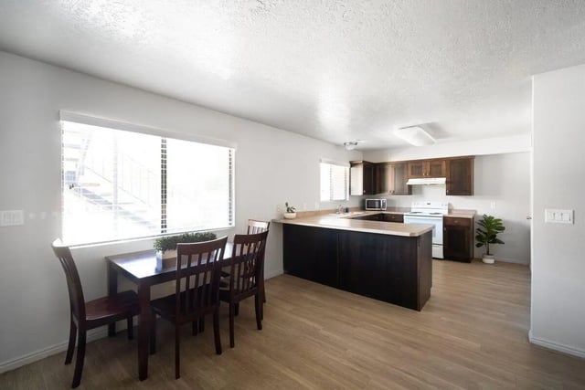 Dining table chairs kitchen with cabinets and appliances kitchen at 7th & University Apartments in St. George Student Accommodation