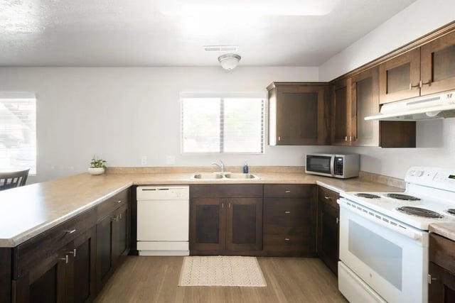 Dark cabinets sink dishwasher microwave oven kitchen at 7th & University Apartments in St. George Student Accommodation