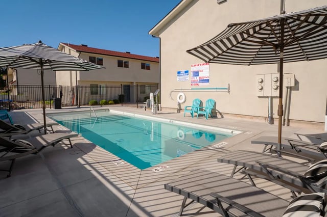 Pool with lounge chairs and umbrellas outdoor area at 7th & University Apartments in St. George Student Accommodation