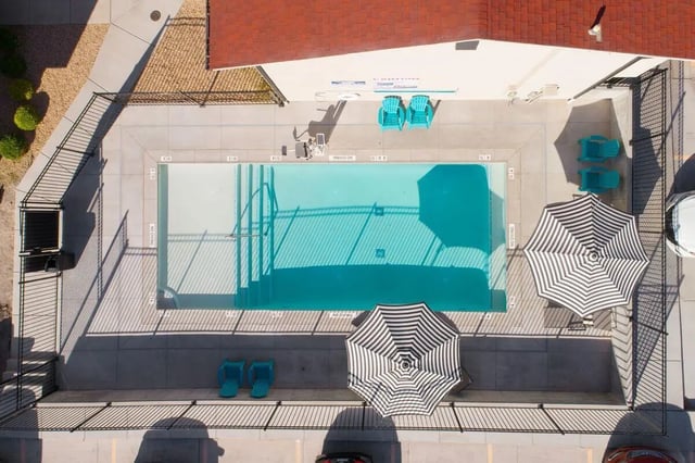 Pool chairs umbrellas and outdoor swimming pool exterior at 7th & University Apartments in St. George Student Accommodation