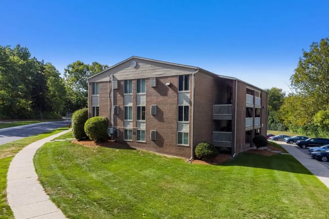 Brick apartment building with balconies and parking exterior at Campus Hill Apartments
